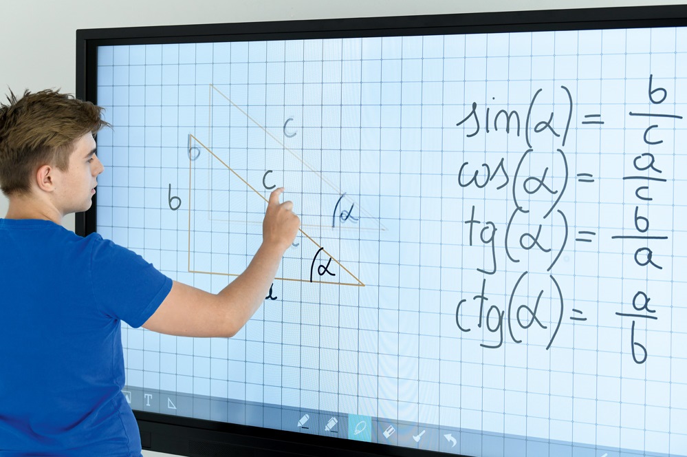 Uczeń rozwiązujący zadanie na tablicy interaktywnej w szkole